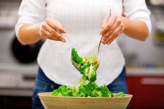 Young woman making salad in the kitchen