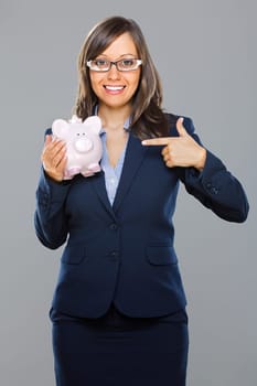 Businesswoman holding pink pig money-box isolated on gray background smiling