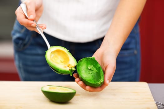 Young woman making salad in the kitchen - peeling avocado