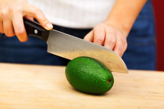 Young woman making salad in the kitchen - peeling avocado