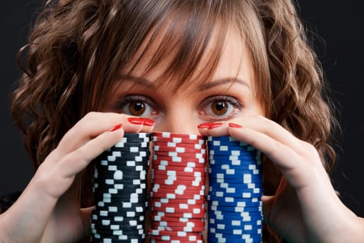 Young woman with gambling chips on black background