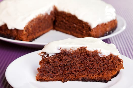 Chocolate cake with white cream, from above with one piece cut from the whole cake