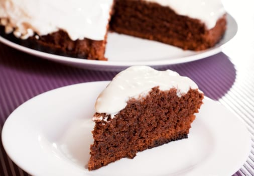 Chocolate cake with white cream, with one piece cut from the whole cake