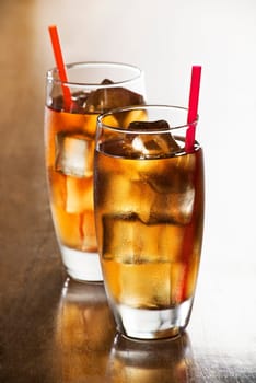 Glass of iced tea with straws and slices cubes.
