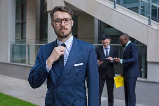 Portrait of multi ethnic business team.Three men standing against the background of city. The foreground of a European man. Other men is Chinese and African-American. The concept of success of the transaction
