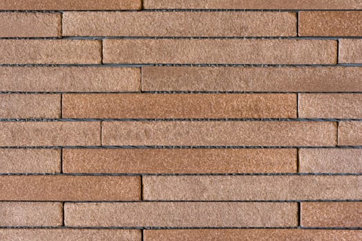 An interior wall of a house covered with long and thin brown bricks.
