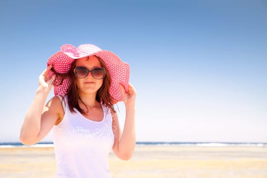 Woman in a pink hat on the sunny beach.