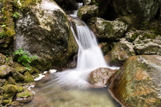 Waterfall mountain river,blurred water between stones with moss