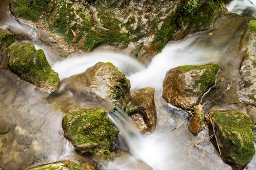 Waterfall mountain river,blurred water between stones with moss