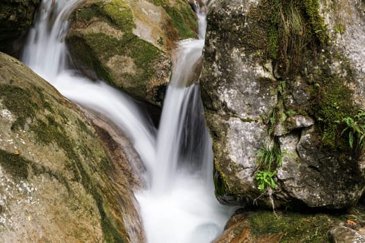 Waterfall mountain river,blurred water between stones with moss