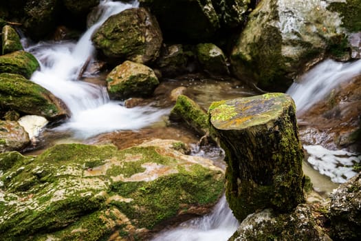 Waterfall mountain river,blurred water between stones with moss