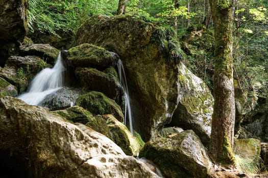 Waterfall mountain river,blurred water between stones with moss