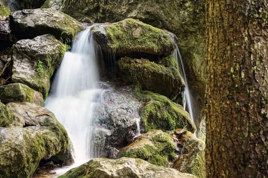 Waterfall mountain river,blurred water between stones with moss