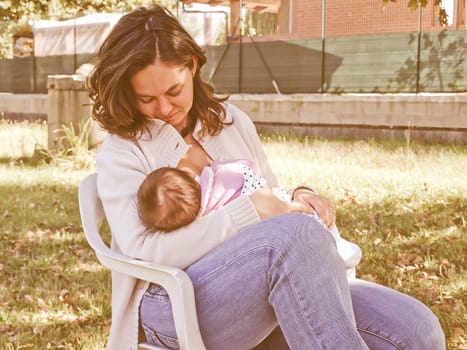 Vintage looking Pretty young brunette mum breastfeeding her baby