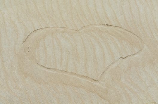 Heart drawn in the sand. Beach background. Plan.