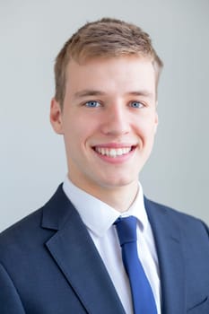 Close up portrait of a formally presented young man, smiling for the camera on a white background