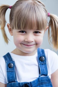 Cute young girl in dungarees smiling at the camera
