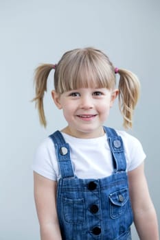 Cute young girl in dungarees smiling at the camera
