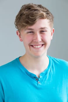 Portrait of a teenage boy against a plain background. He is smiling for the camera.