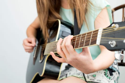 Close up image of a young girl playing guitar.