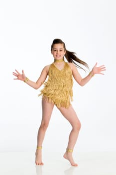 Young female dancer in gold costume. She is dancing against a white background and smiling for the camera.
