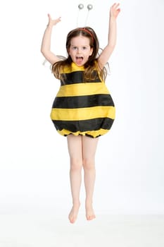 Little girl in a bumble bee costume posing in midair against a white background