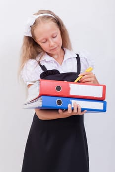 Schoolgirl  holding folders in her hands and  writing something over white background