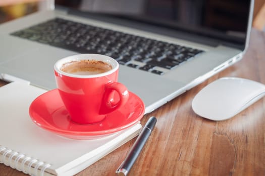 Red coffee cup with notepad and laptop, stock photo