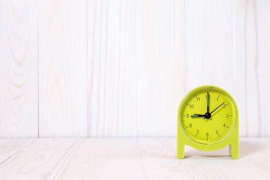 Green alarm clock on wood background. With copy-space for text