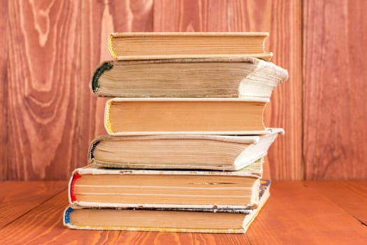 Old books stacked on wood texture background, knowledge concept