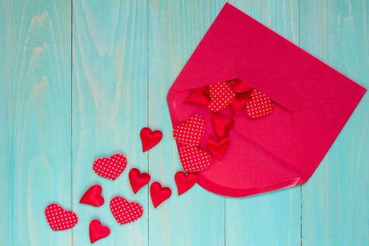 Envelope with red hearts on the blue wooden background