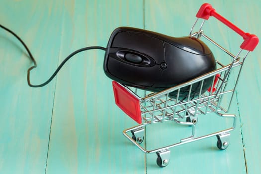 Shopping cart with a computer mouse on blue background