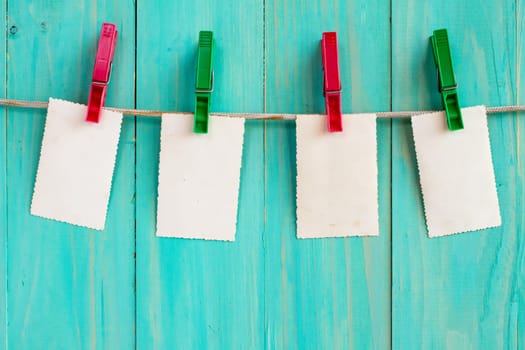 Photo frames hanging on a rope over blue wooden background
