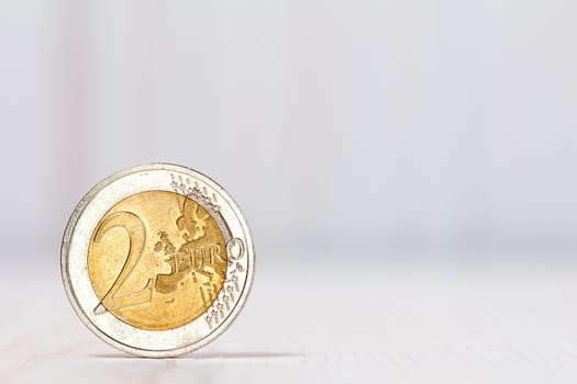 Two euros coin on white wood background. With copy-space for text