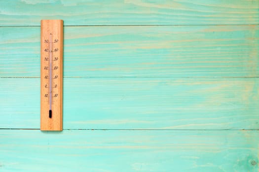 Thermometer on the wooden wall showing high temperature near 30 degrees