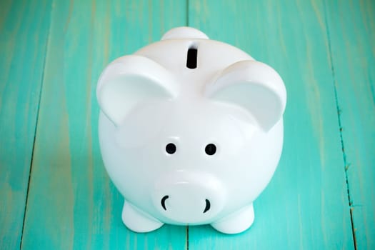 White piggy bank on the blue wooden background