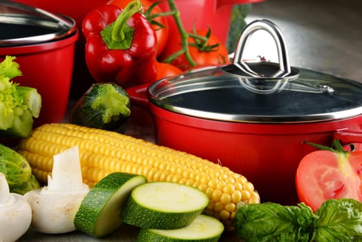 Composition with red steel pots and variety of fresh vegetables.