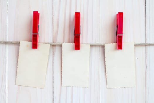Photo frames hanging on a rope over white wooden background
