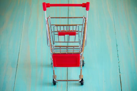 Empty mini shopping cart against wooden background