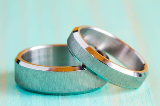 Two white gold rings on the blue wooden surface