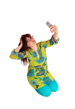 A middle age pretty woman kneeling on the floor, taking a selfie with her.smartphone, isolated for white background..