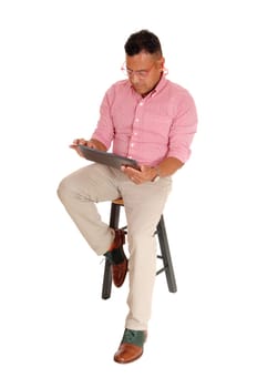 A middle age man sitting on a chair with safety glasses and earplug's working.with his tablet computer, isolated for white background..