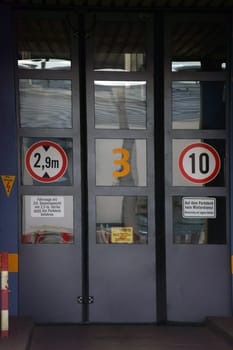 A factory entrance with swingdoors or gates and traffic signs.