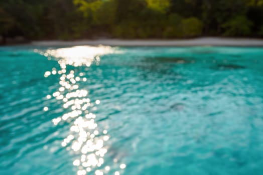 Blur beach and green blue sea surface with reflecting sunlight evening in summer for background