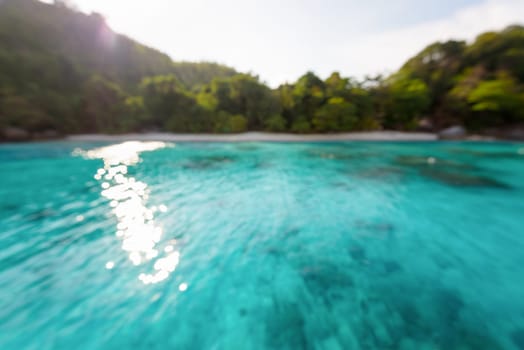 Blur beach and green blue sea surface with reflecting sunlight evening in summer for background
