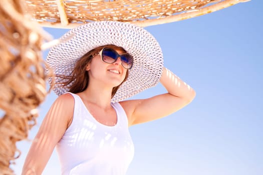 A young pretty woman in a hat on the beach.