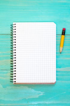 Open notebook and pencil on the blue wooden surface