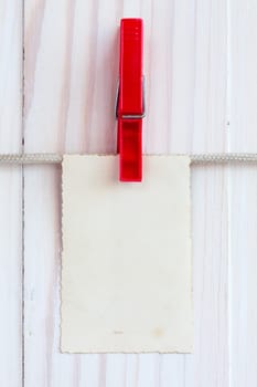 Photo frame hanging on a rope over white wooden background