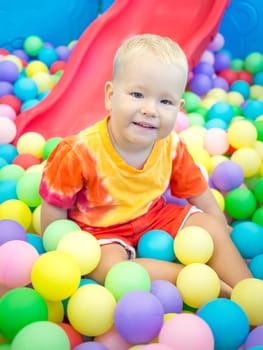 Cute kid boy playing with colorful balls