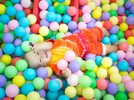 Cute kid boy playing with colorful balls